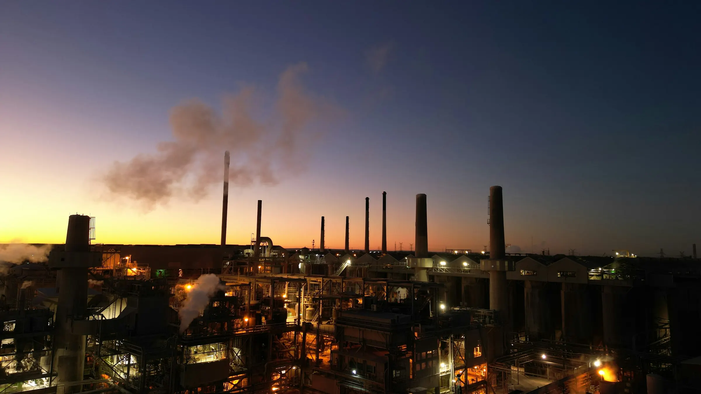 An industrial plant with smoking stacks at dusk